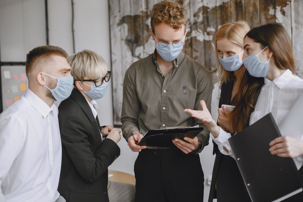 Group of professionals wearing masks discussing strategies indoors.